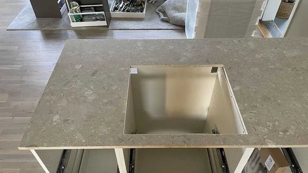 Top-down vy av matt Terrazzo Perlato Royal på en kökshalvö med öppet urtag och ljusa stenkorn under montering i Smygehamn.