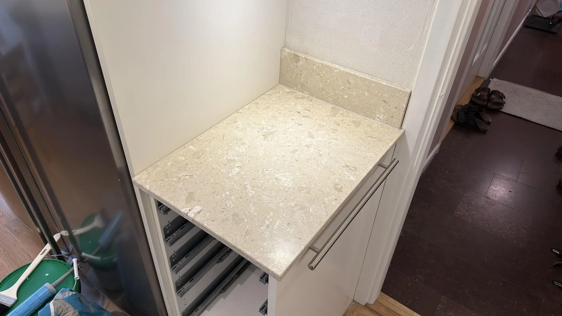 Sidobänk i matt Terrazzo Perlato Royal med matchande stänkkant och beige stenflisor i ett kök i Solna.