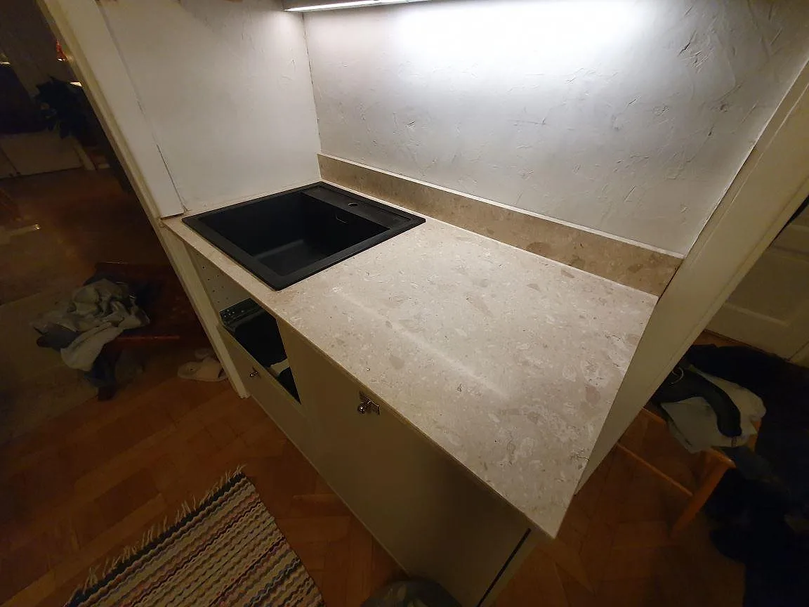 Matt terrazzobänkskiva i Terrazzo Perlato Royal med svart underlimmad kompositdiskho och uppvikt stänkkant i ett kök i Stockholm.