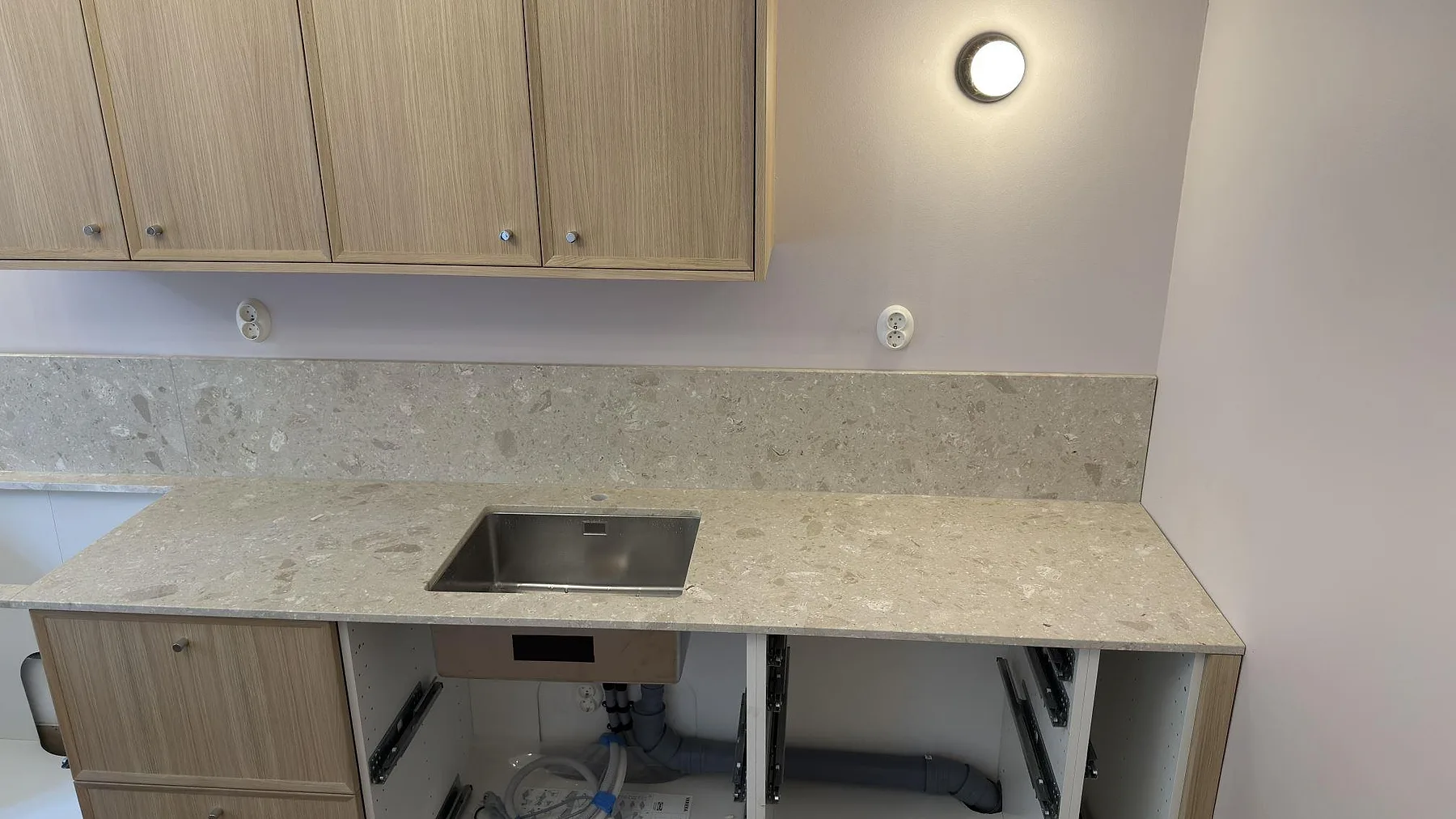 Närbild av matt Terrazzo Perlato Royal som köksbänkskiva med diskho och stänkskydd i Stockholm.