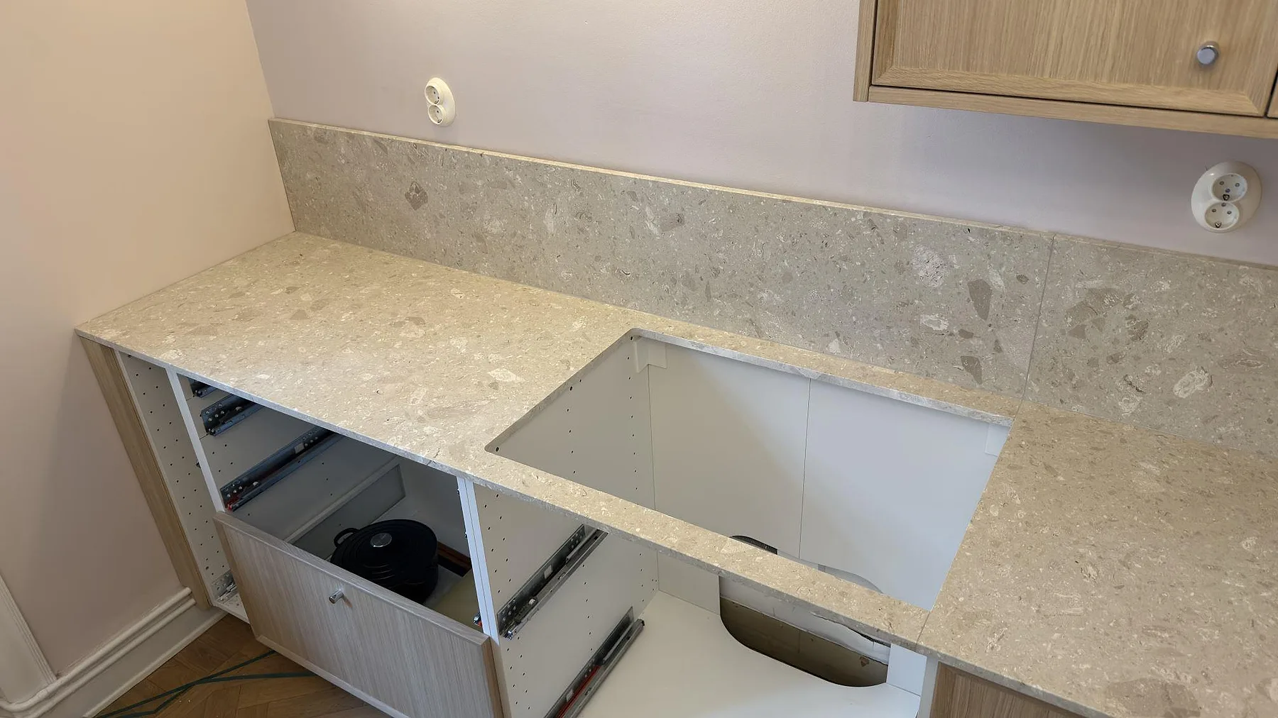 Matt köksbänkskiva i Terrazzo Perlato Royal med urtag för häll och uppvikt stänkskydd i Stockholm.