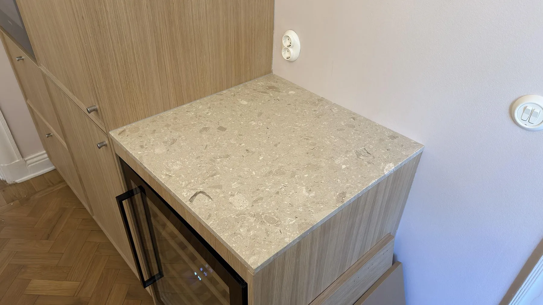 Sidobänk i matt Terrazzo Perlato Royal ovanför köksinredning med träytor i Stockholm.