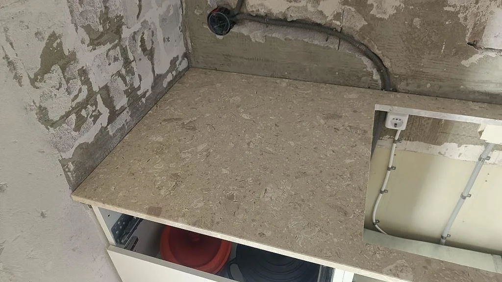 Närbild på matt Terrazzo Perlato Royal köksbänkskiva med beige terrazzomönster och öppet urtag i ett kök i Ystad.
