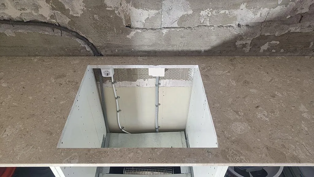 Köksbänkskiva i Terrazzo Perlato Royal, matt beige terrazzo, sedd ovanifrån över vita stommar under montering i Ystad.