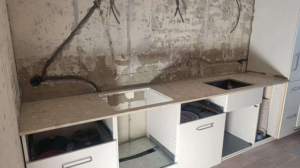 Rak köksbänkskiva i matt Terrazzo Perlato Royal, 20 mm, med underlimmad rostfri diskho i ett kök under montering i Ystad.