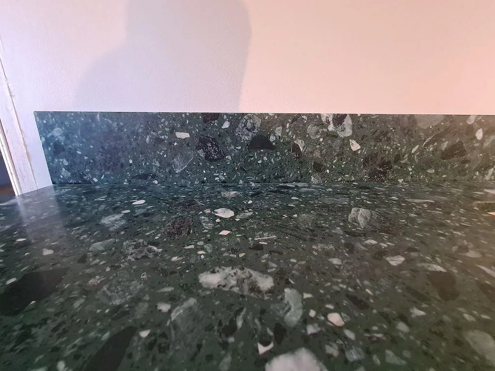 Närbild av matt Terrazzo Verde Alpi som köksbänkskiva med matchande stänkskydd i Stockholm.