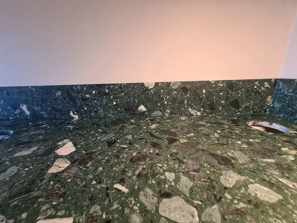 Låg detaljbild av matt Terrazzo Verde Alpi med stänkskydd och blandarhål i ett kök i Stockholm.