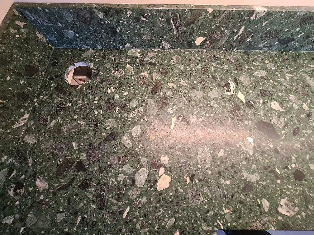 Ovanifrån syns den matta Terrazzo Verde Alpi ytan med stänkskydd och blandarhål i köket i Stockholm.