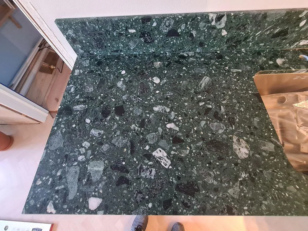 Köksbänkskiva i Terrazzo Verde Alpi, matt, med matchande stänkskydd och rostfri diskho under montering i Stockholm.