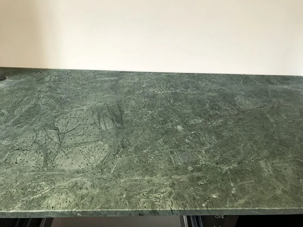 Bänkskiva i grön Verde Guatemala marmor med matt grön yta mot ljus vägg i ett kök i Göteborg.