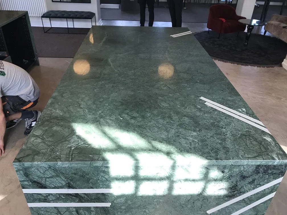Stor köksö i grön Verde Guatemala marmor sedd ovanifrån under montering i ett kök i Göteborg.