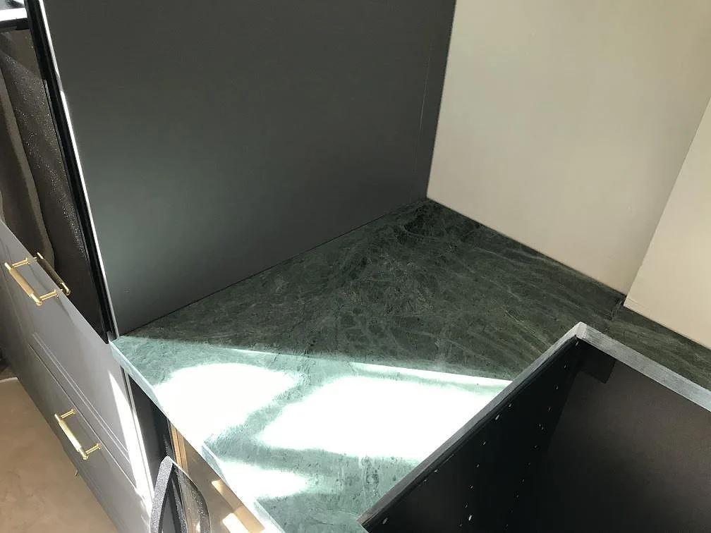 Installerad bänkskiva i Verde Guatemala mot mörkt stänkskydd i ett kök i Göteborg.