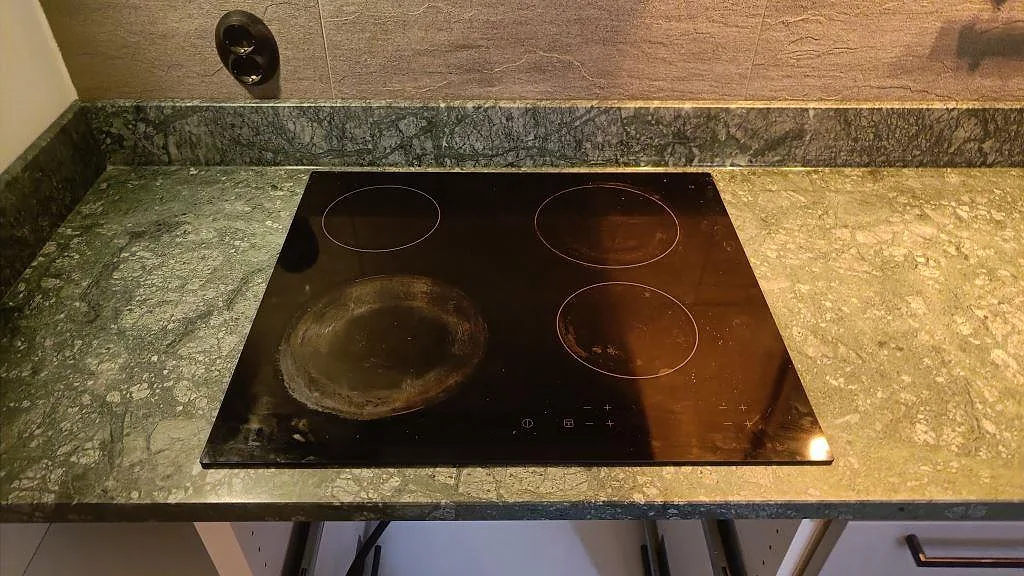 Svart induktionshäll infälld i matt Verde Guatemala-marmor med grön ådring och låg stänkkant i Göteborg.