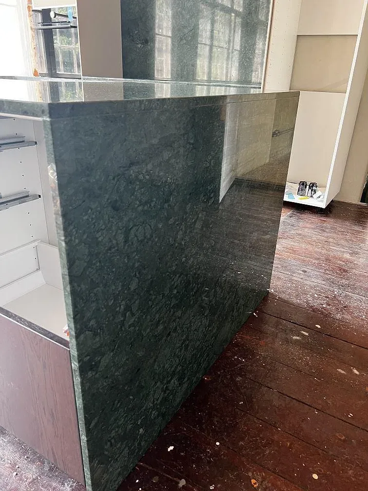 Närbild av tjugo millimeter polerad Verde Guatemala marmor på köksö under montering i Jelling.