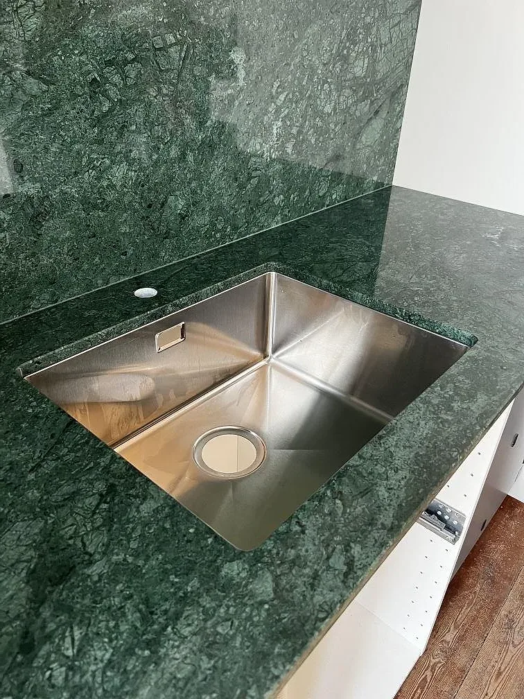 Detalj av polerad Verde Guatemala marmor med underlimmad diskho i ett kök i Jelling.