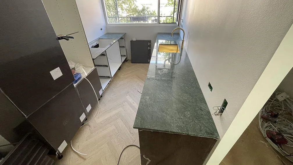 Köksbänkskiva i grön Verde Guatemala marmor, polerad, monterad i ett smalt kök under arbete i København.