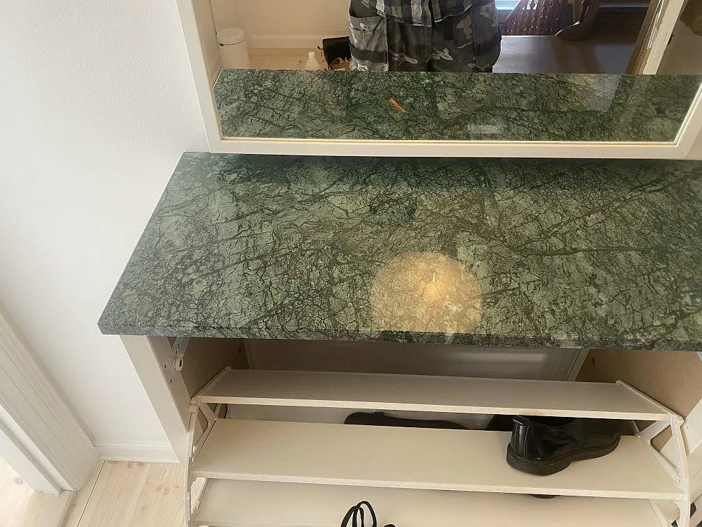 Närbild av polerad Verde Guatemala marmor med grön ådring på installerad konsolskiva under spegel i København N.