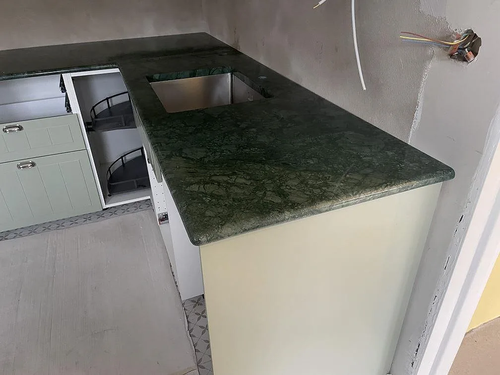 Polerad Verde Guatemala marmorskiva med rostfri diskho och rundad framkant på en arbetsyta i ett kök i Staffanstorp.