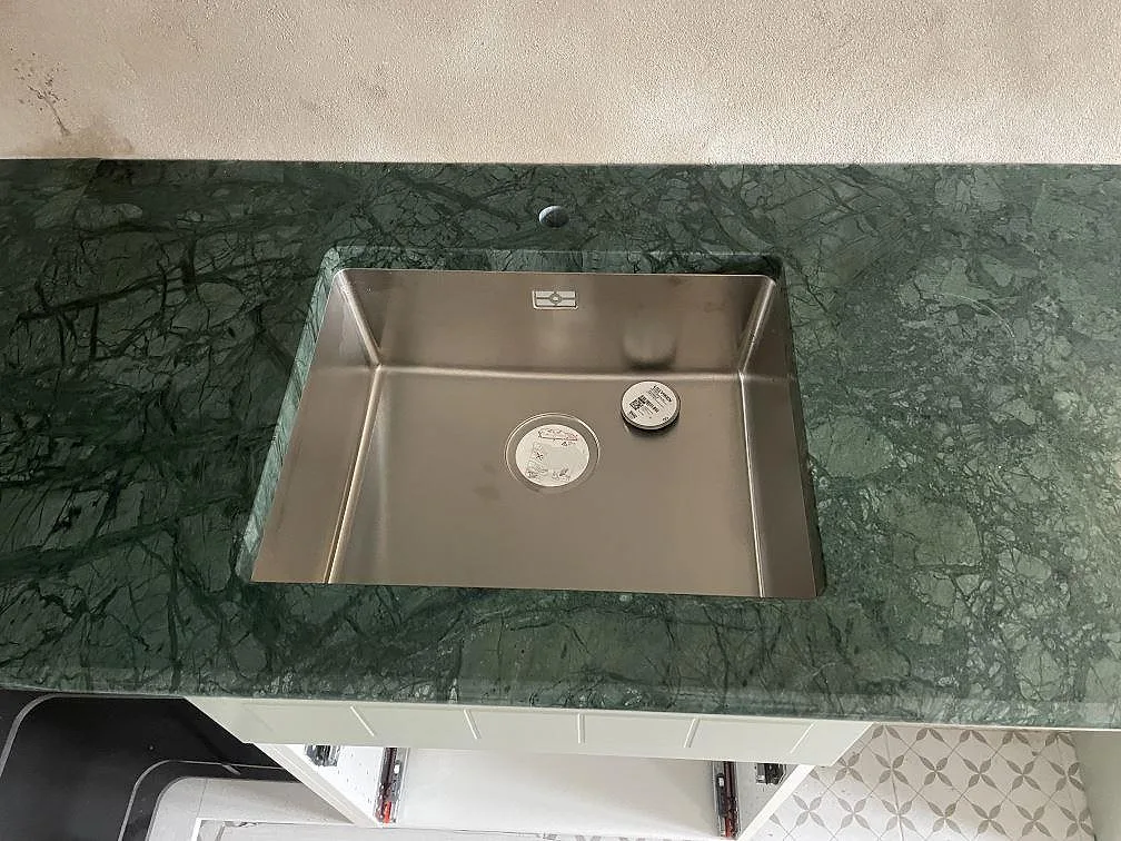 Rostfri diskho i polerad Verde Guatemala marmorbänkskiva med borrat blandarhål och mörkgrön ådring i Staffanstorp.