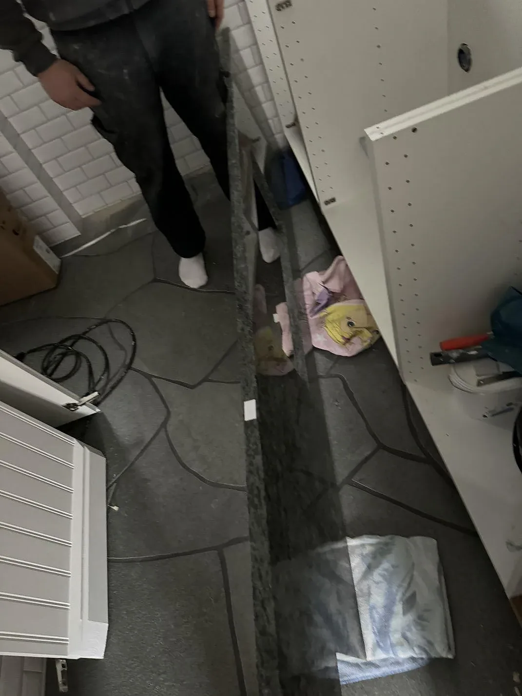Detalj av 30 mm polerad Verde Savana granit som smal köksbänkskiva över radiator vid vita skåpstommar i Bara.