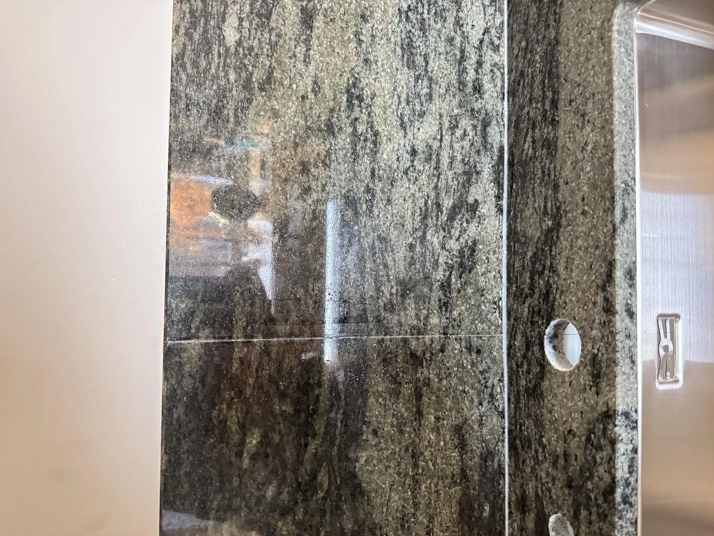 Vertikal detalj av polerad Verde Savana granit vid diskho och håltagning i ett kök i Bunkeflostrand.