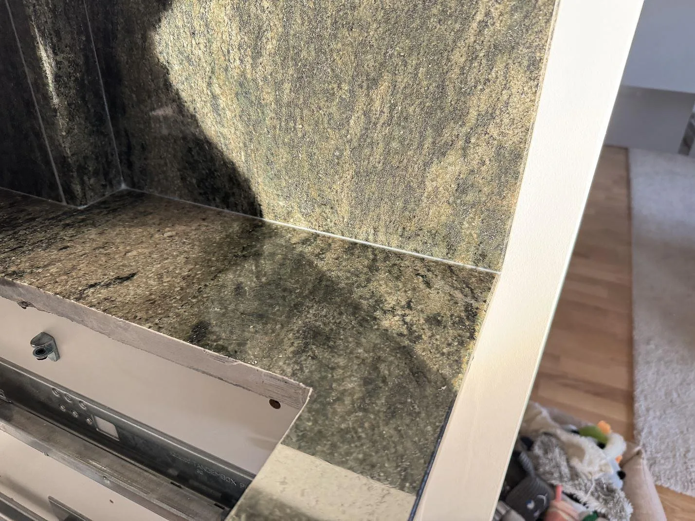 Sidodetalj av Verde Savana granit där bänkskiva och stänkskydd möts vid en öppen köksstomme i Bunkeflostrand.
