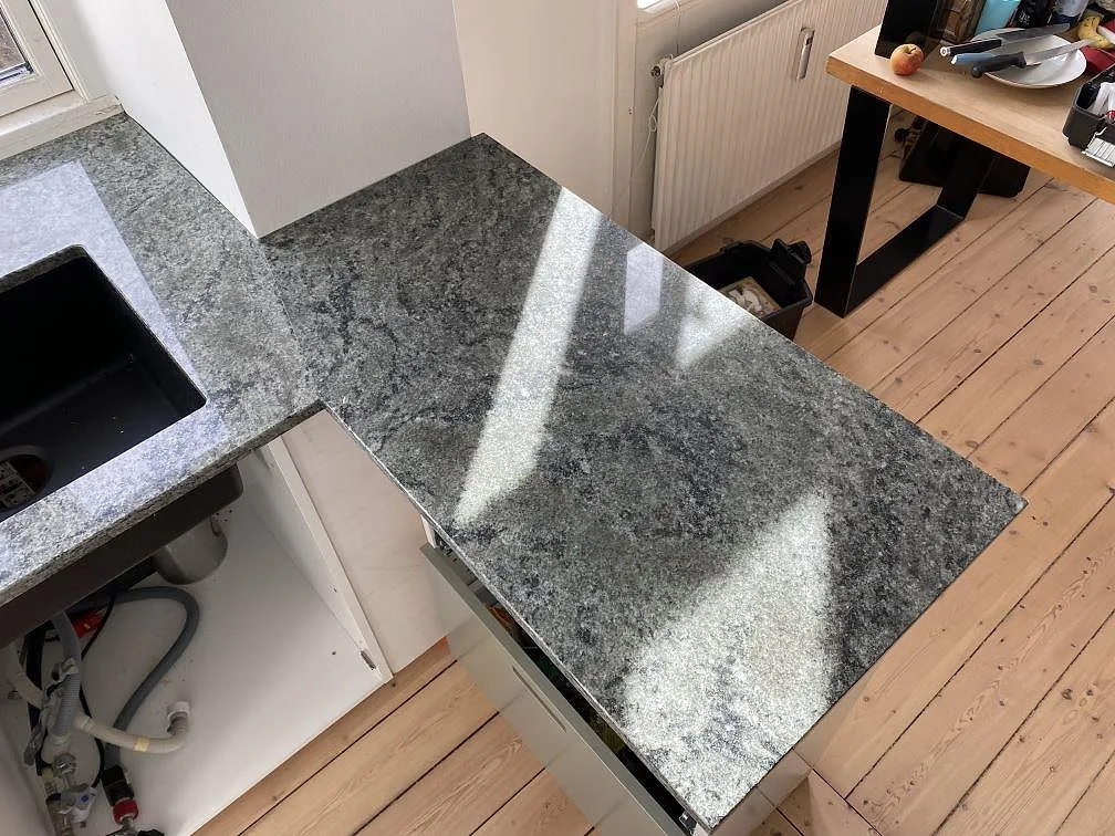 Hörndetalj av polerad Verde Savana granit med sammanfogade köksbänkskivor och öppen stomme i Frederiksberg Danmark.