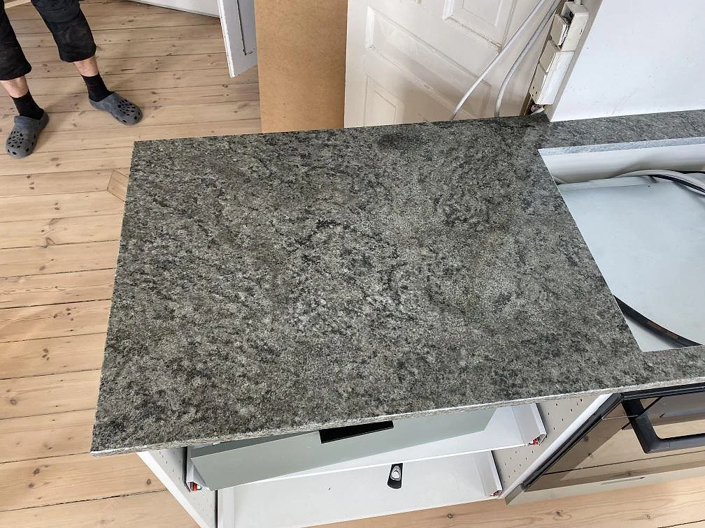 Detalj av polerad Verde Savana granit på en mindre köksbänkskiva under montering i Frederiksberg Danmark.