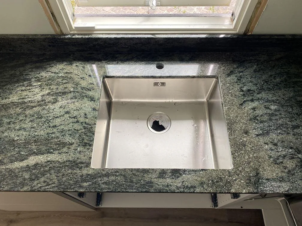 Detalj av diskhozonen i polerad Verde Savana granit i Kävlinge, med synlig diskho under fönstret och grönsvart ådring.