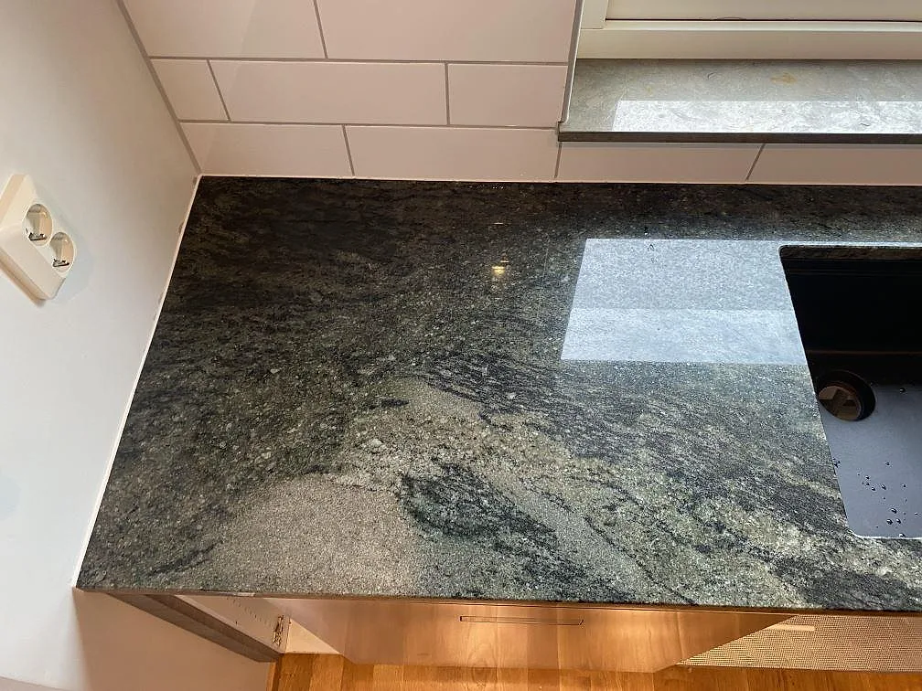 Närbild av polerad Verde Savana granit vid diskhozonen, med blank yta och grönsvart ådring i Klagshamn.