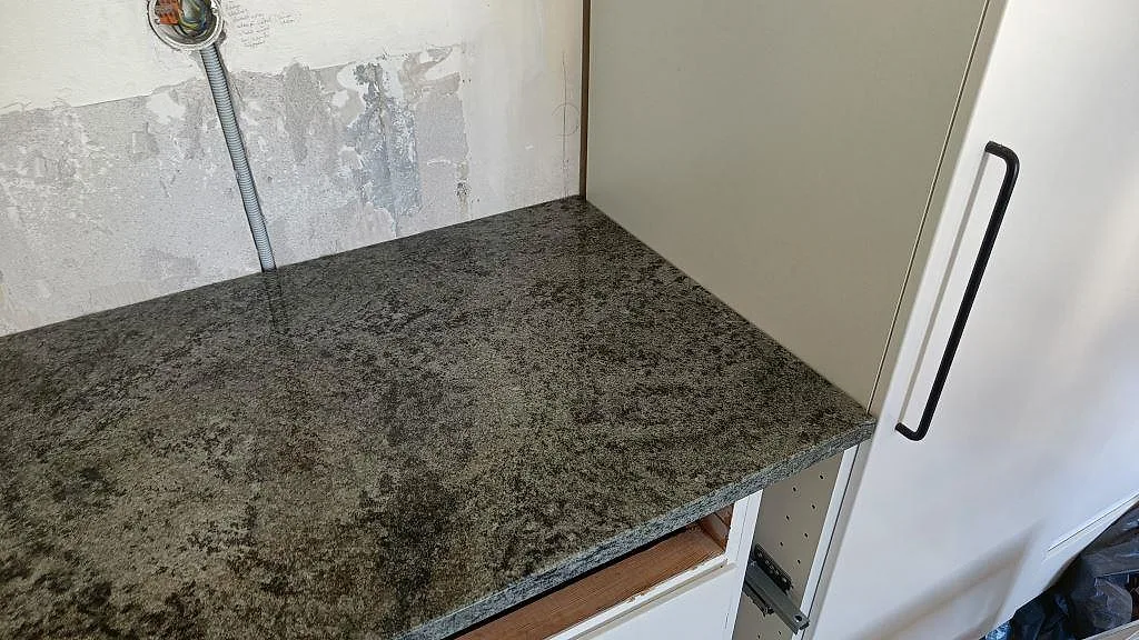 Köksbänk i Verde Savana granit som vänder runt ett hörn, polerad yta med synlig granitådring, i ett kök i Landskrona.