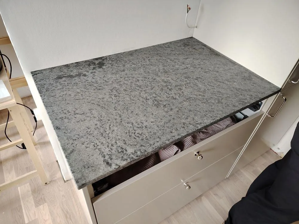 Närbild av matt Verde Savana granit på en rak köksbänkskiva över vita stommar i Lidingö.