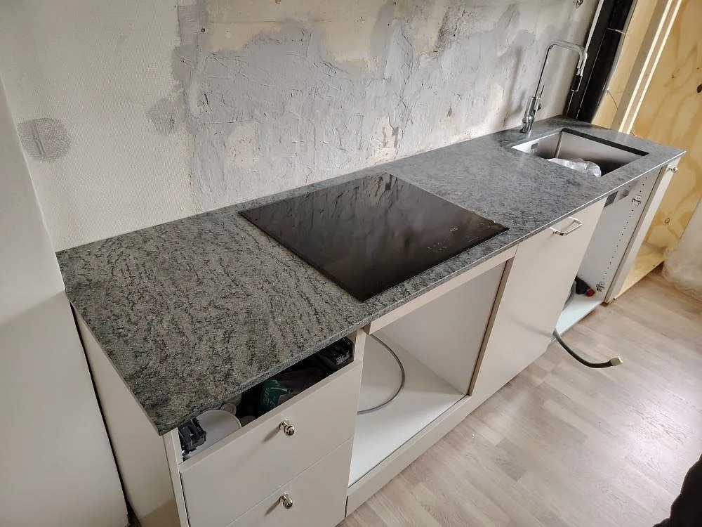 Matt Verde Savana granit som köksbänkskiva med häll och diskho i ett pågående köksmontage i Lidingö.