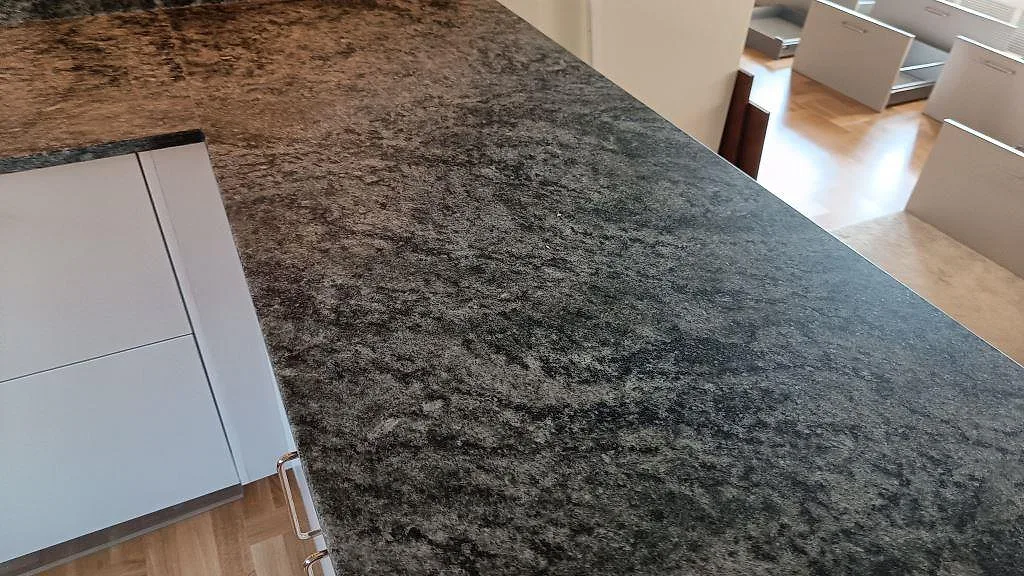 Närbild på den virvlande grågröna ytan i matt Verde Savana granit på köksbänken i Limhamn.