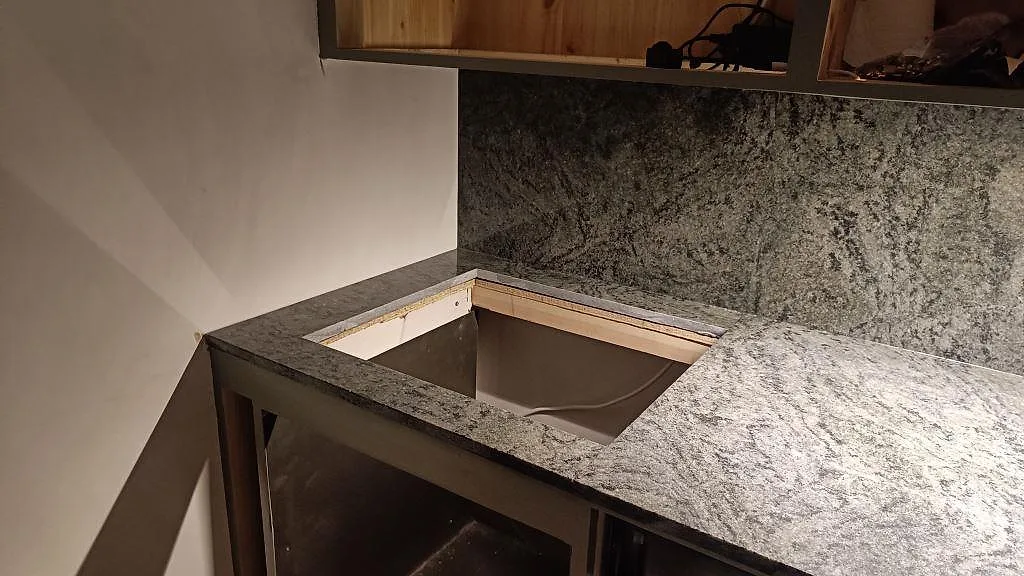 Detalj av polerad Verde Savana granit runt en stor öppning i köksbänken och matchande stänkskydd i Malmö.