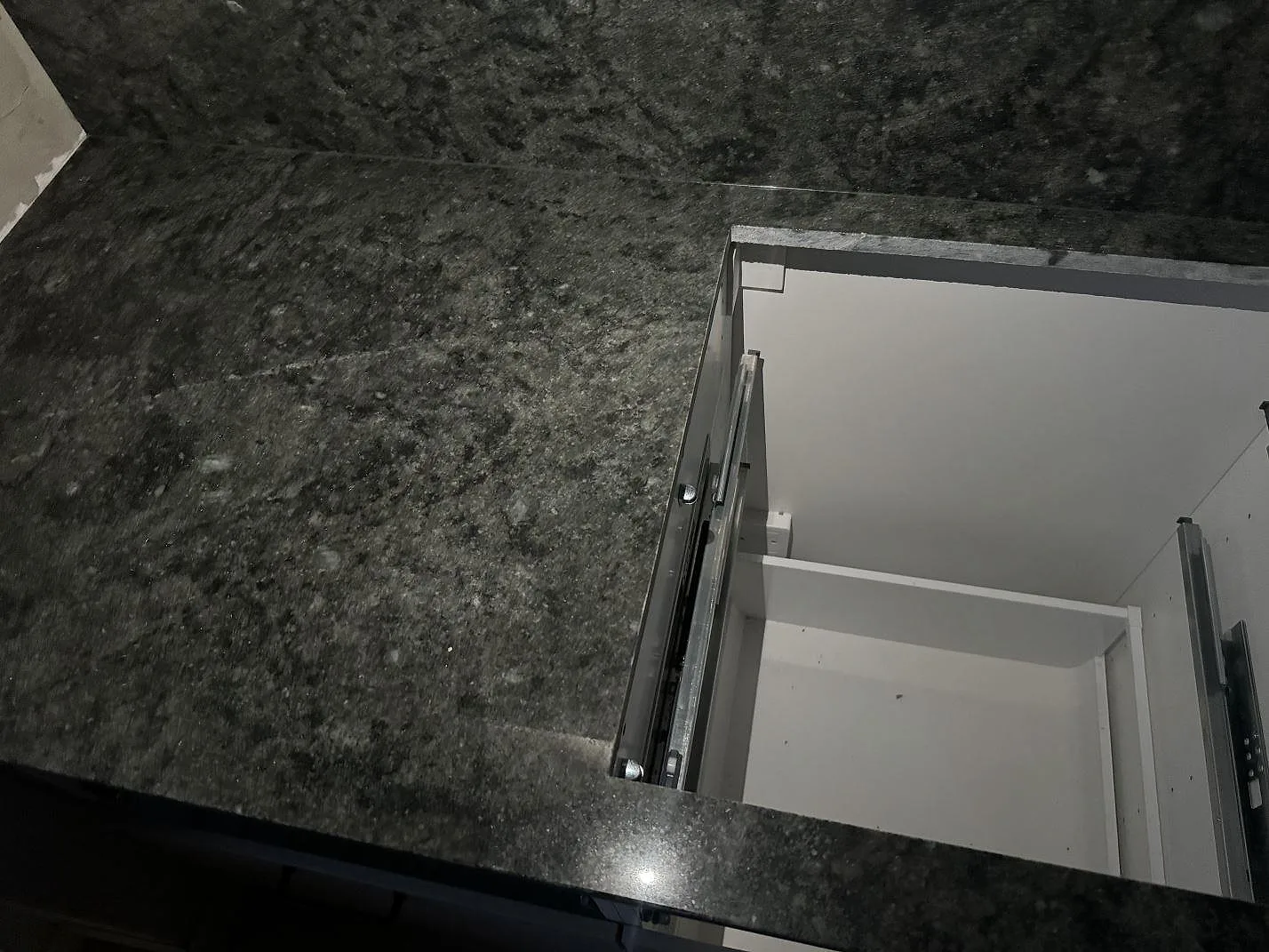 Detalj av polerad Verde Savana granit vid öppen köksstomme med mörk ådring och stänkkant i Malmö.