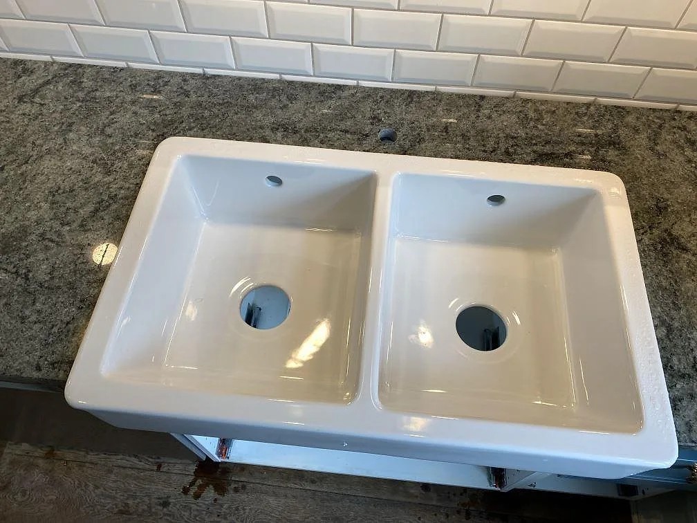 Detalj av polerad Verde Savana granit runt en vit dubbelho under montering i Svedala.
