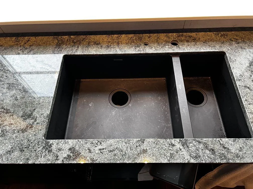 Detalj av den dubbla underlimmade diskhon i en polerad Verde Savana köksbänkskiva i Vallåkra.