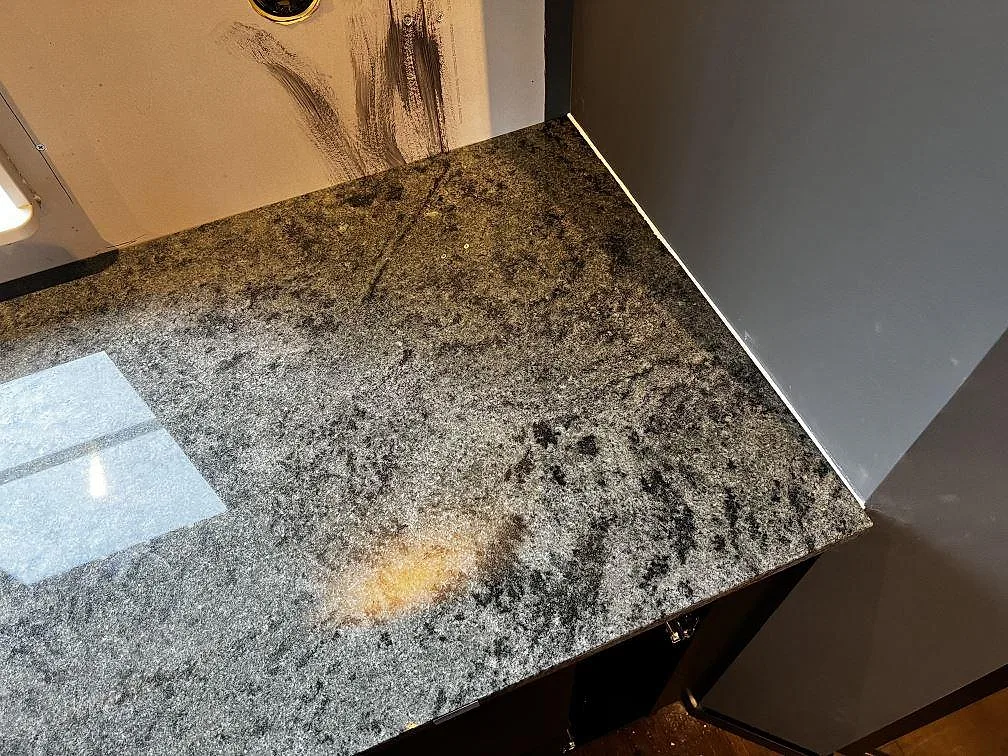 Installerad hörndel av köksbänkskiva i polerad Verde Savana granit vid väggskiva i Vallåkra.