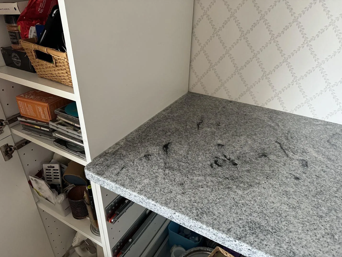 Detalj av installerad Viscont White köksbänkskiva i polerad granit intill öppen vit förvaring i Bjärred.