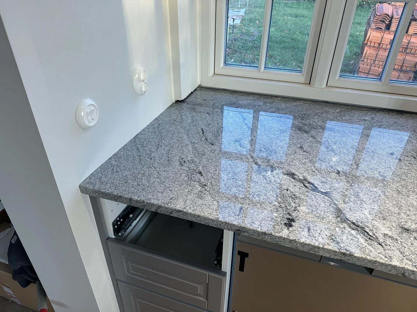 Polerad Viscont White granit på köksbänk under fönster med öppna stommar under montering i Broddetorp.