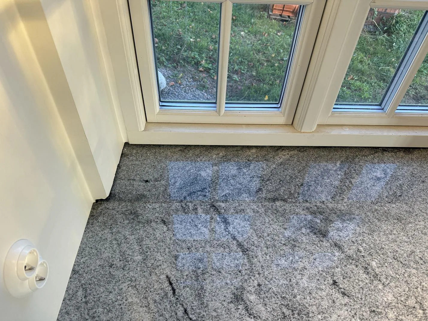 Detalj av polerad Viscont White granit med fönsterreflexer i köket i Broddetorp.