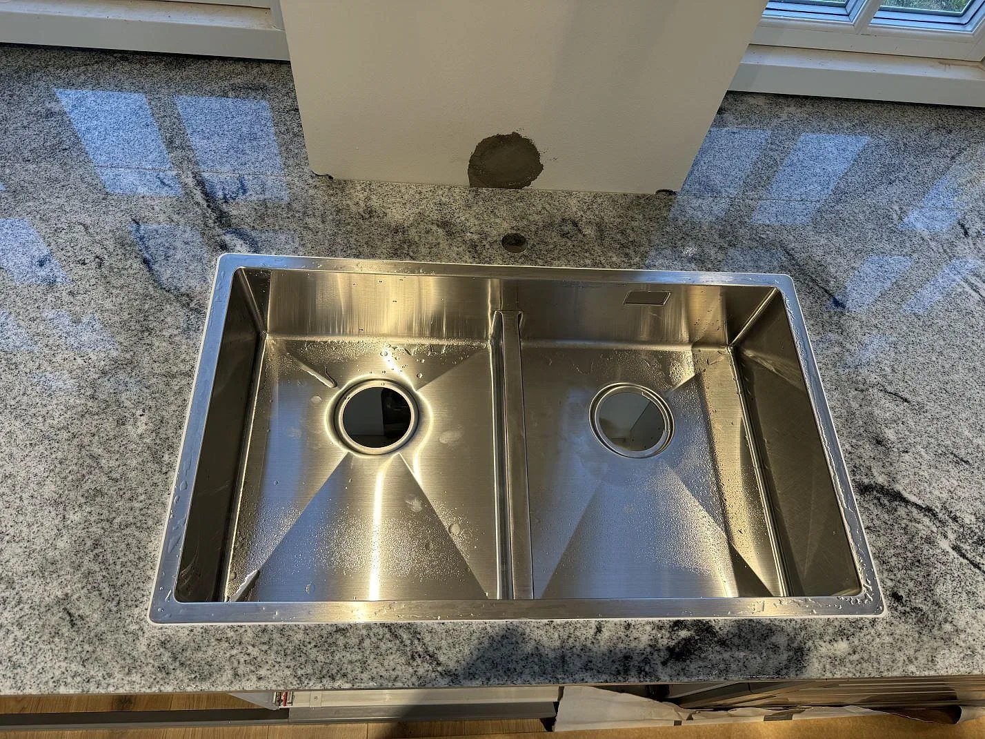 Detalj av rostfri diskho i polerad Viscont White granit med fönsterreflexer i Broddetorp.