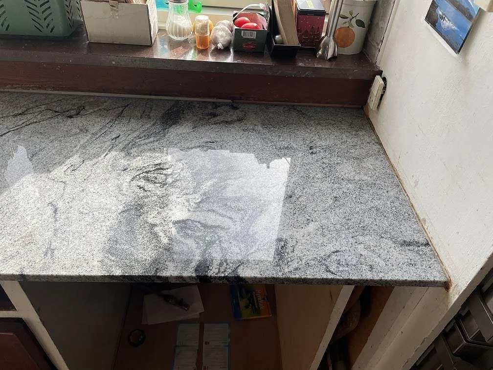 Köksbänkskiva i Viscont White, polerad vit och grå granit med flödande grå ådring, sedd uppifrån i ett kök i Charlottenlund.