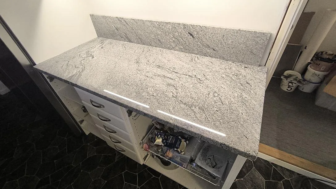 Närbild på polerad Viscont White granit som köksbänkskiva med stänkskydd och tydlig grå ådring i Ekolsund.