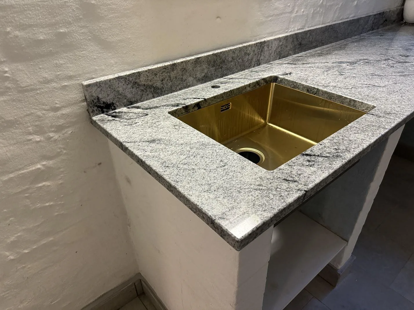 Polerad Viscont White granit runt en mässingsfärgad underlimmad ho i ett grovkök i Frederiksberg.