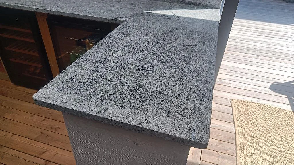 Närbild på polerad Viscont White granit i ett utekök i Göteborg, med ljus bänkskiva och synlig grå ådring.