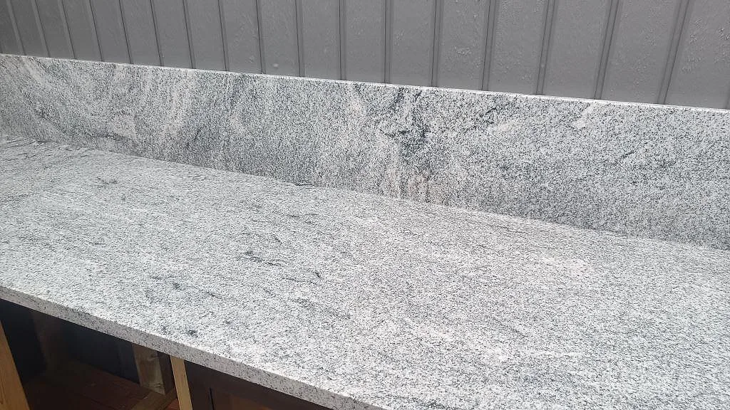 Lång bänkskiva i polerad Viscont White granit med uppvikt stänkkant i ett utekök i Göteborg.