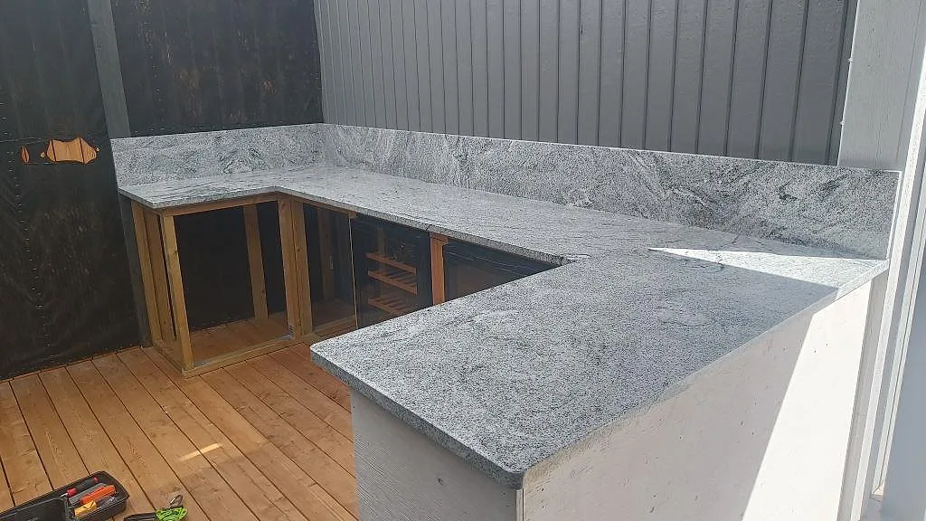 Utekök i Göteborg med polerad köksbänkskiva i Viscont White granit, uppvikt stänkkant och U-formad montering på trädäck.