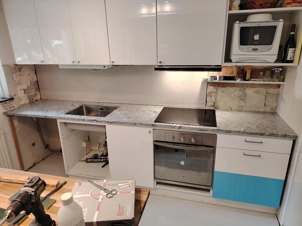 Köksbänkskiva i vit och gråspräcklig Viscont White granit, polerad, med kort stänkskydd och induktionshäll i ett kök i Hässelby.